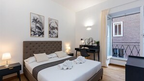 A modern hotel room with a large bed, bedside tables, a desk, and a balcony with a view. - Elegant apartment in Via della Frezza, near Piazza di Spagna / Spanish Steps (Rome)