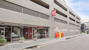 En bygning med et skilt for 'Manly National 22 Central Avenue' og et skilt for 'Postshop'.