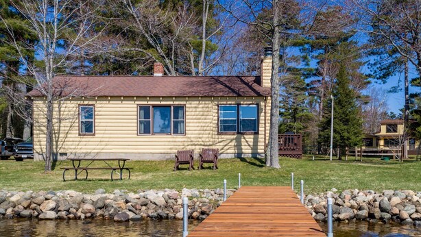 A wooden dock leading to a house with a chimney, a picnic table, and two benches. - Comfy pet friendly 2 bedroom with fireplace (Saint Germain)