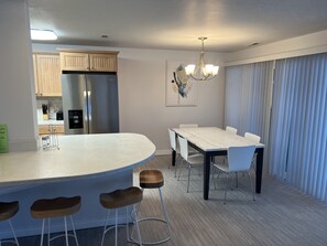A modern kitchen with a central island, white chairs, and a dining table.