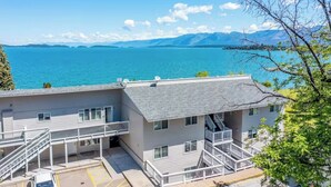 A multi-story building with a balcony overlooking a body of water and mountains. - The Flathead Overlook at Lakeplace (Polson)