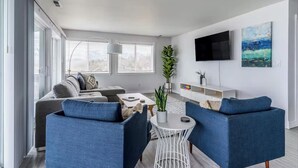 A modern living room with a sofa, two armchairs, a coffee table, and a TV mounted on the wall. - The Flathead Overlook at Lakeplace (Polson)