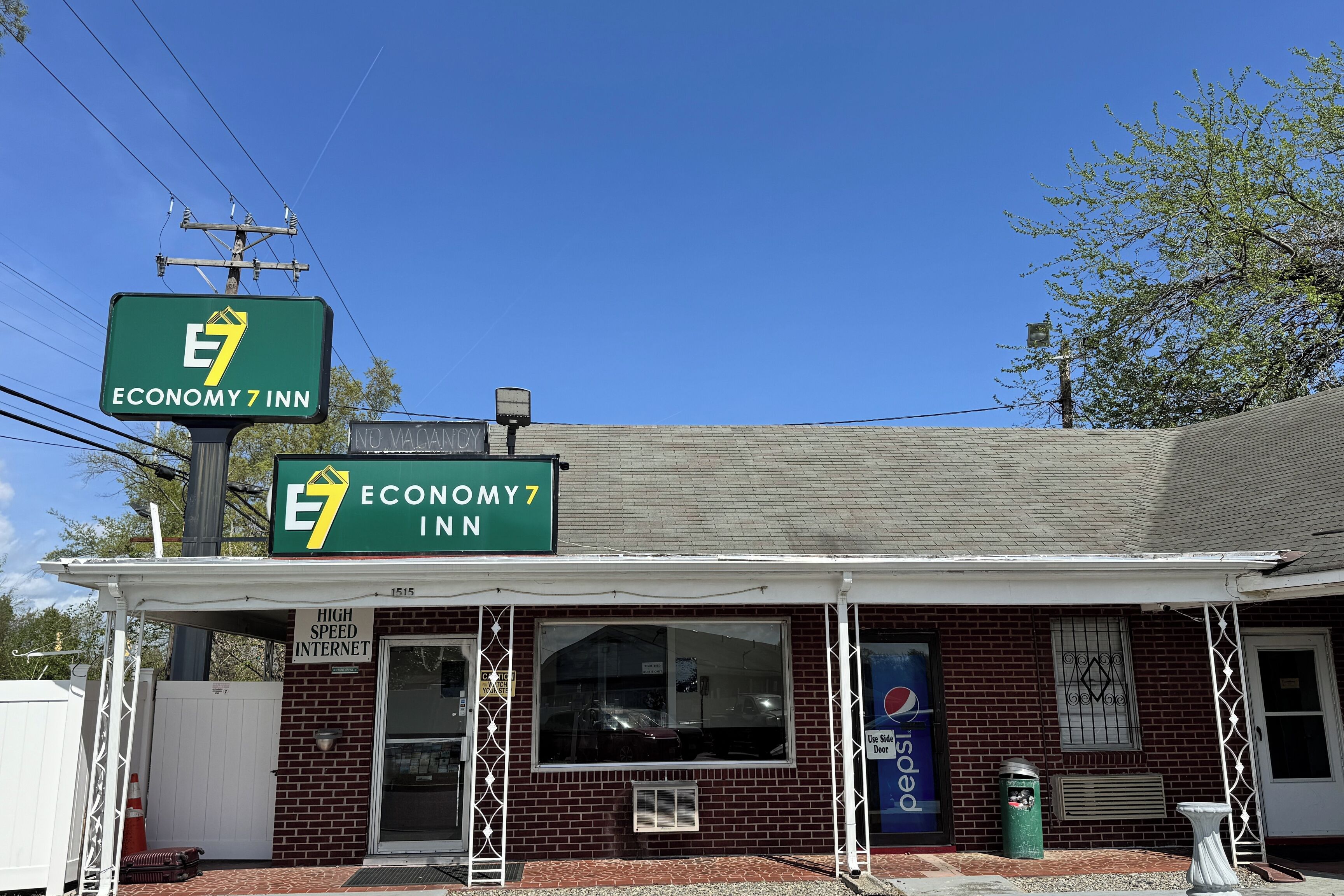 A brick building with a green sign for Economy 7 Inn, a large window, and a Pepsi advertisement.