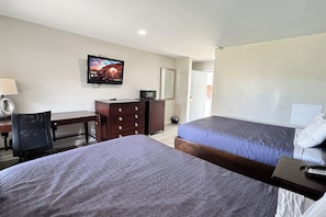 A hotel room with two beds, a desk, a chair, a television, and a dresser. - Economy 7 Inn Near Hampton University VA (Hampton)