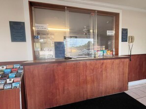 A reception desk with a glass partition, a phone, and various informational signs.