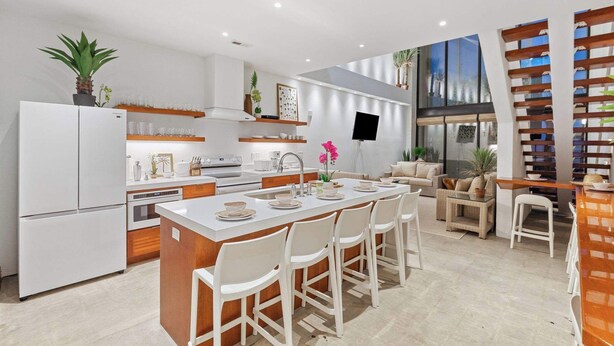 A modern kitchen with a central island, white appliances, and a dining area with white chairs. - Vacation Villa 5 mins to King ‘The Royal Palm’ (Charleston)