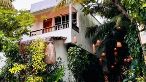 A two-story building with a balcony, surrounded by lush greenery and palm trees. - Odi Kamadhoo (Kamadhoo)