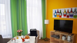 A hotel room with a dining table set with breakfast items, a TV, and a coffee machine. - Posthus Apartment 201, close to the beach and central (Borkum)