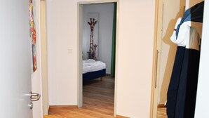 A hallway with wooden flooring leading to a bedroom with a bed and a decorative item. - Posthus Apartment 201, close to the beach and central (Borkum)