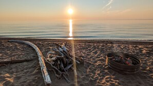A beach scene with a sunset, a fire pit, and driftwood.