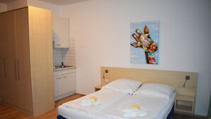 Una camera da letto con un letto, un comodino, un quadro e un angolo cottura.