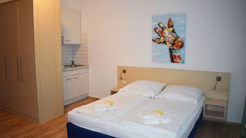 Ein Schlafzimmer mit einem Bett, einem Nachttisch, einem Gemälde und einer Küchenzeile.