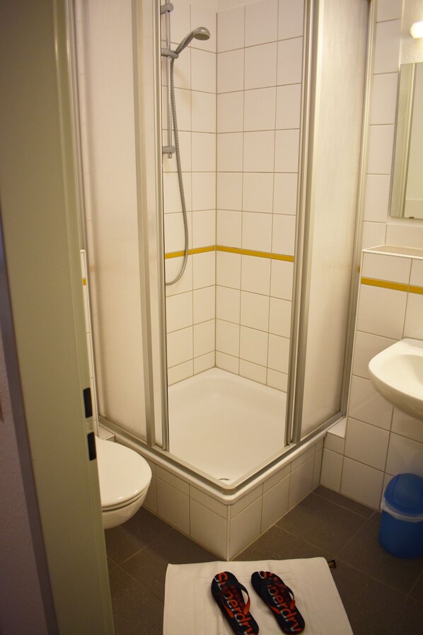 A small bathroom with a shower, toilet, and sink.