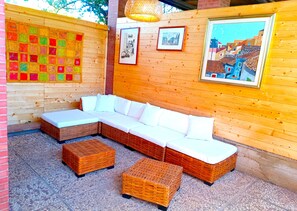 A wooden interior with a sectional sofa, wicker ottomans, and framed pictures on the walls.