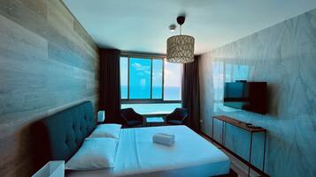 Une chambre d’hôtel moderne avec un grand lit, une télévision et une vue sur la mer.