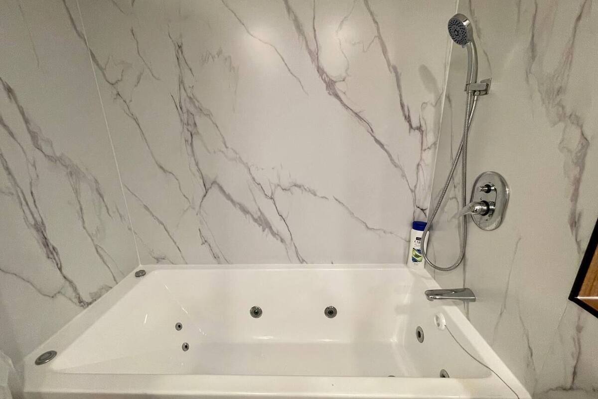 A modern bathroom with a freestanding bathtub, a handheld showerhead, and a wall-mounted faucet.
