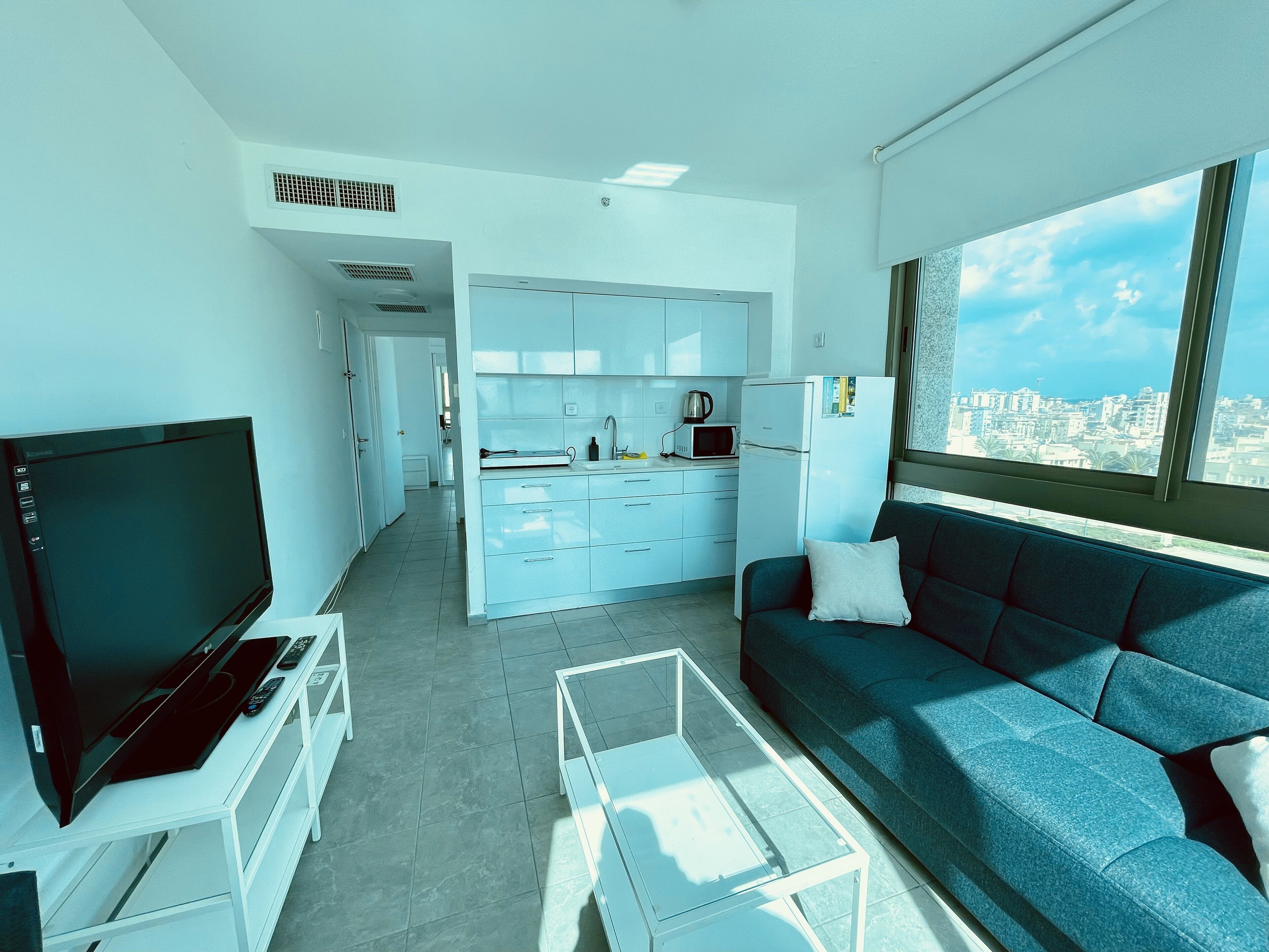 Una sala de estar moderna con una televisión de pantalla plana, un sofá y una mesa de centro.