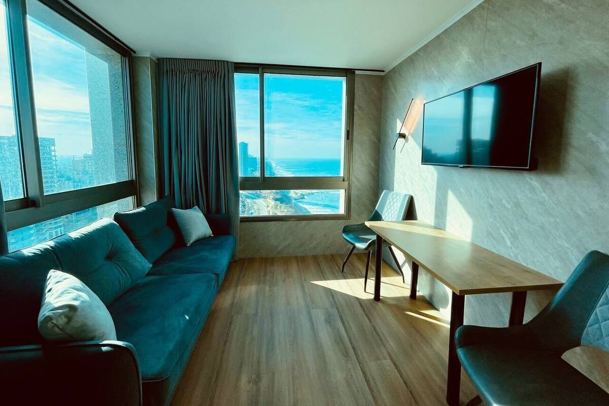 A modern living room with a sofa, a dining table, and a TV.