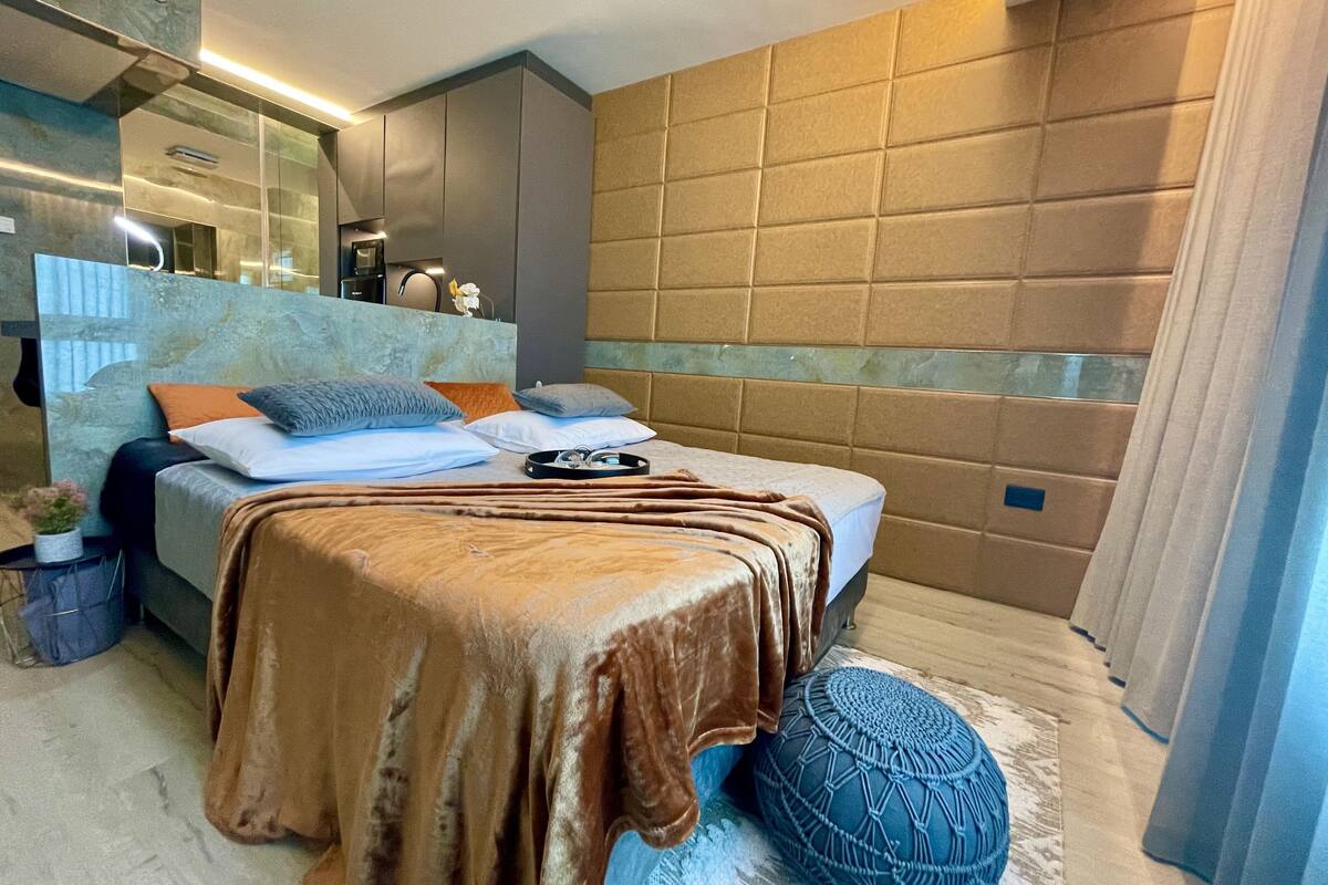 A modern bedroom with a bed, bedside table, and a large window.