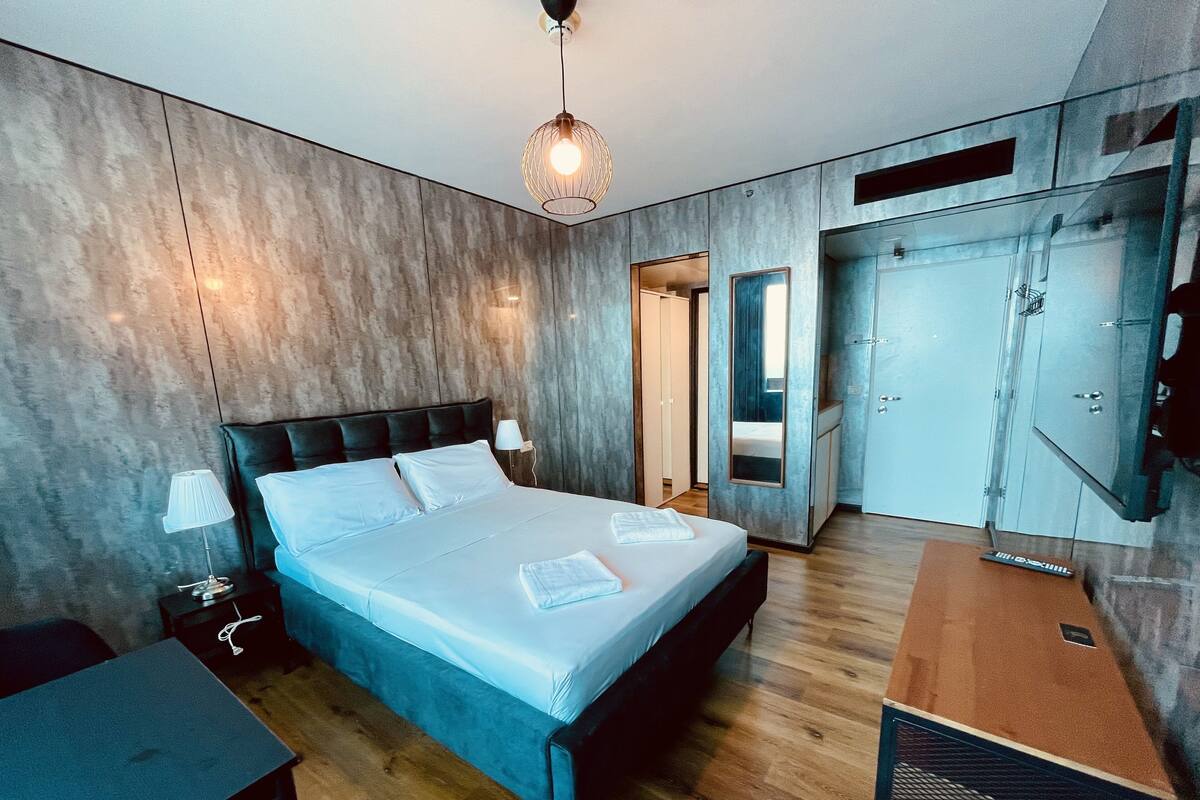 A modern bedroom with a large bed, bedside tables, a wardrobe, and a television.