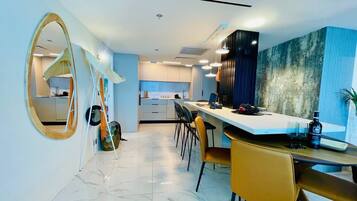 A modern dining area with a long table, yellow chairs, and a large mirror on the wall.