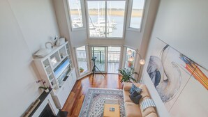 Un salon spacieux doté d’une grande fenêtre donnant sur une marina, d’un canapé confortable, d’une cheminée et d’une bibliothèque.