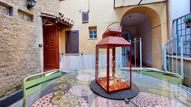 A courtyard with a glass table surrounded by patterned floor tiles, a red lantern, and a green chair. - 4BNB - Cozy Vatican Loft with Terrace (Roma)