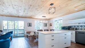 A modern kitchen with white cabinetry, a central island, and a dining area with blue chairs.