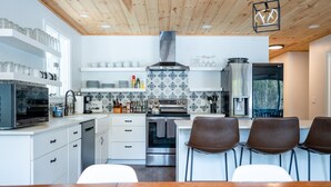 A modern kitchen with white cabinetry, a stainless steel range, and a wooden ceiling.