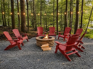 A fire pit surrounded by red Adirondack chairs in a forest setting. - BearHaus Central AC, HUGE Hot Tub, Awesome FirePit (Killington)