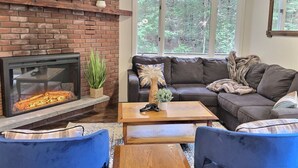 A cozy living room with a brick fireplace, a leather sofa, and a wooden coffee table.
