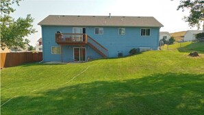 A two-story house with a front deck and a well-maintained lawn. - 5 Bedroom Home for your Black Hills Adventures (Rapid City)