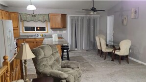 A dining area with a table and chairs, a sofa, a lamp, and a kitchen in the background. - 5 Bedroom Home for your Black Hills Adventures (Rapid City)