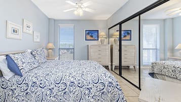 A bedroom with a bed, a dresser, a mirror, and a ceiling fan.