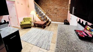 Un espacio habitable compacto con cocina, una escalera y una zona de estar con una lámpara.