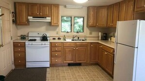 A kitchen with wooden cabinets, a white stove, a sink, and a refrigerator.
