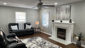 A living room with a black leather sofa, a white fireplace, and a ceiling fan. - Entire beautiful home w/ great location!  (Paducah)