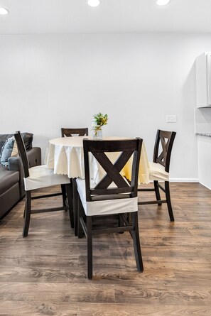 A dining area with a round table, four chairs, and a vase with flowers. - Modern 3BR Furnished Home Near DIA with 2-Car Garage (Denver)