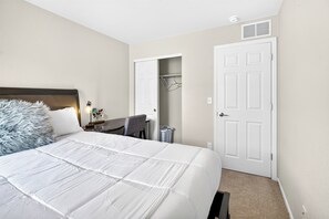 A bedroom with a bed, a desk, and a closet. - Modern 3BR Furnished Home Near DIA with 2-Car Garage (Denver)