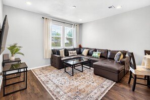 A modern living room with a sectional sofa, a glass coffee table, and a patterned rug.