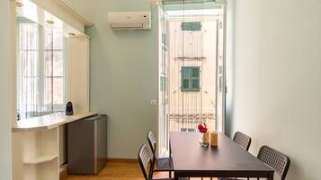 A compact kitchen with a refrigerator, a dining table with chairs, and a window with curtains.