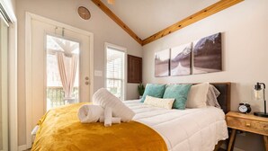 Un dormitorio con cama, mesita de noche, reloj y ventana con persianas.