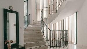 A modern staircase with a metal railing, a large mirror, and a vase with flowers on a console table. - Grace Holon Villa & Pool (Holon)
