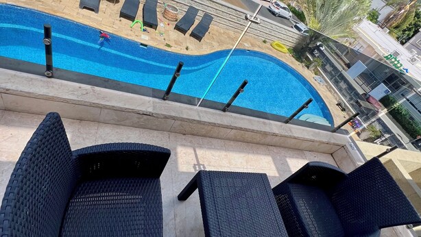 Una piscina con sillas de descanso y una pared de piedra.