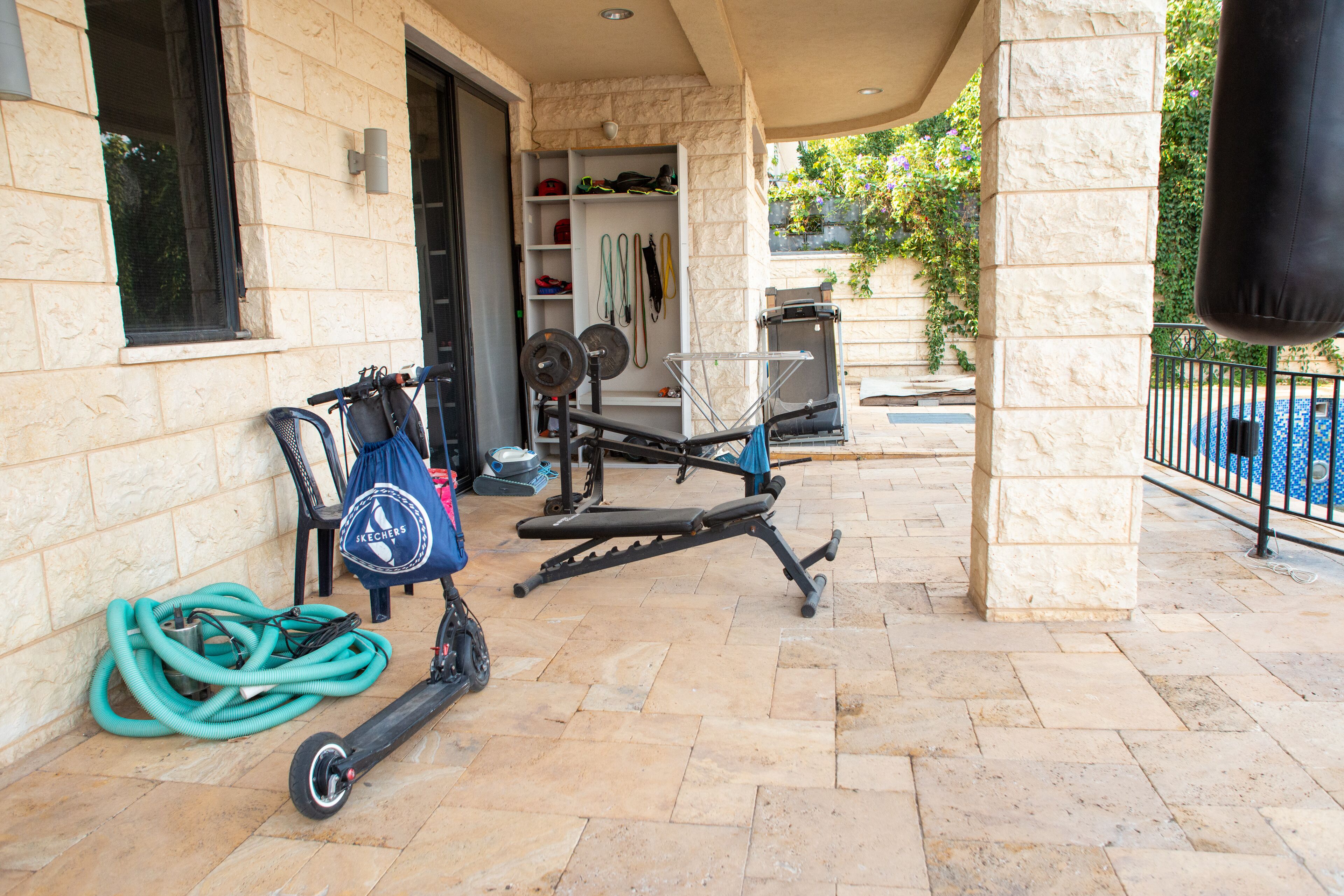 An outdoor gym area with exercise equipment, a water hose, and a bag on the ground.