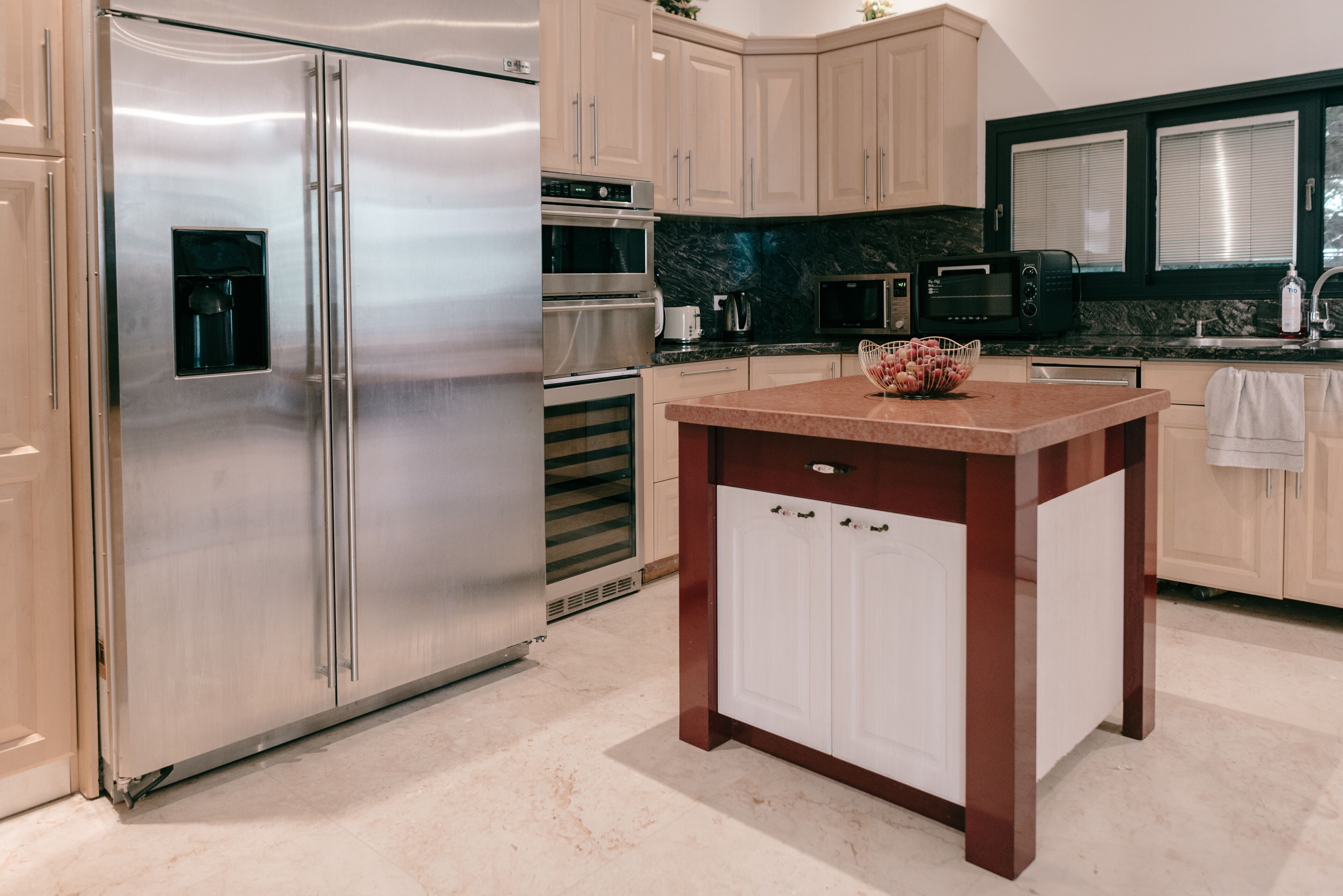 A modern kitchen with stainless steel appliances, a marble countertop, and wooden cabinets.
