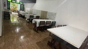 A restaurant with multiple tables and chairs, a tiled floor, and a view of the outdoors.