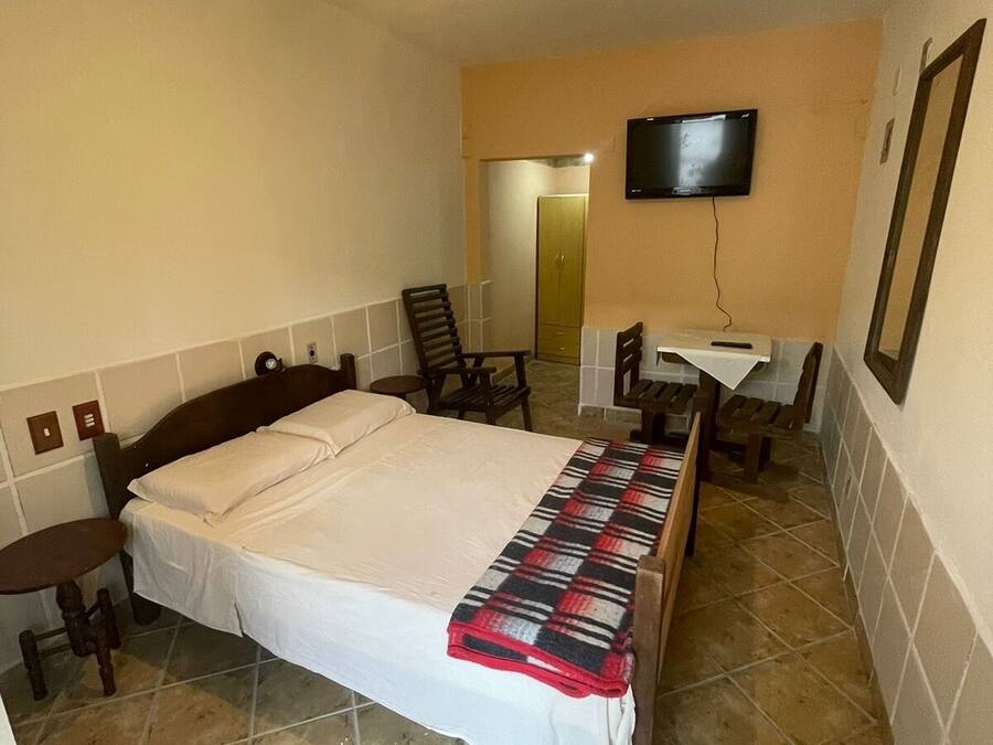 A hotel room with a bed, a television, a desk, and a chair.