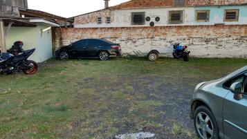Un barrio residencial con un edificio de ladrillo, un coche negro, una motocicleta azul y un remolque.