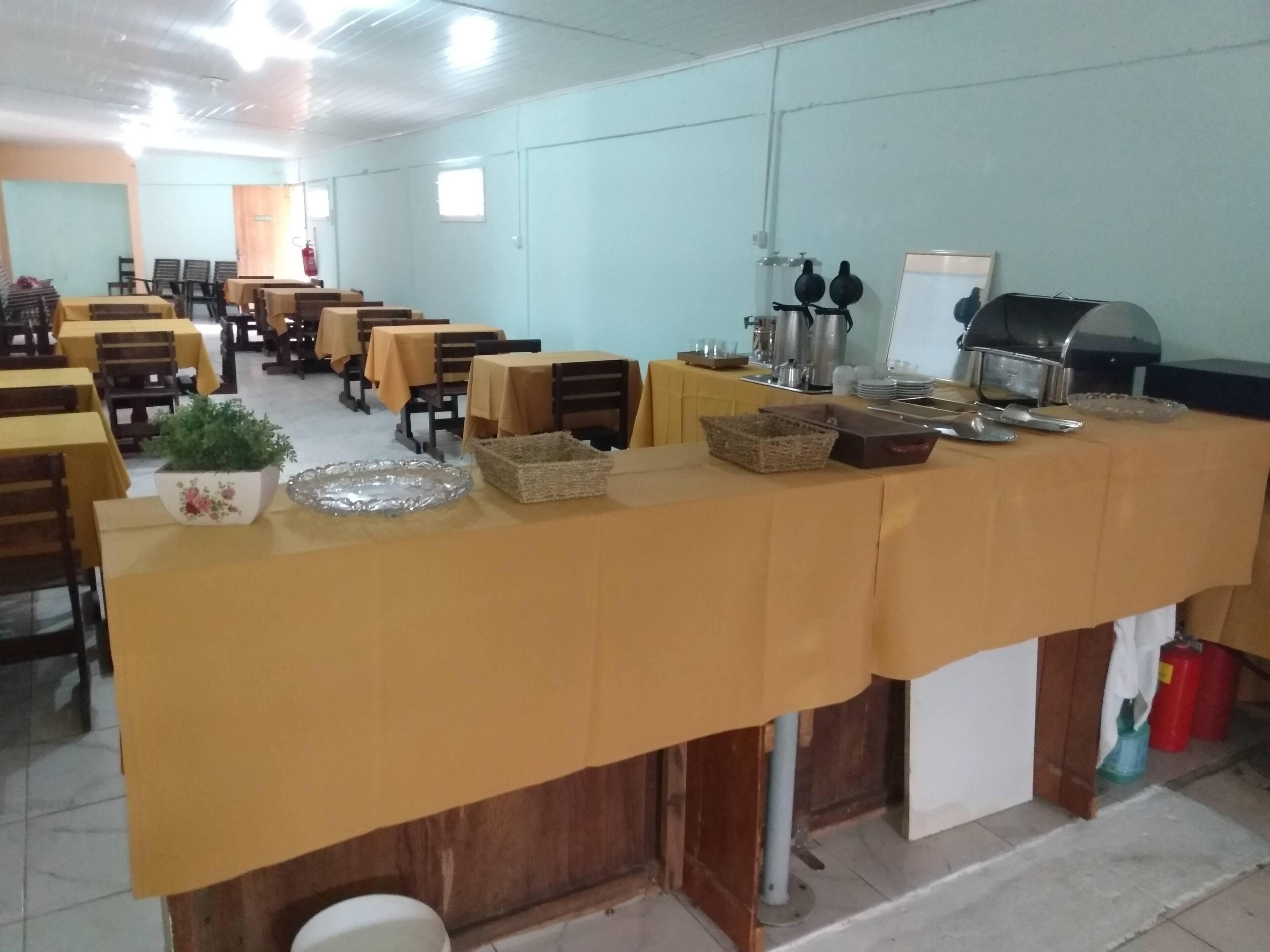 Une cafétéria avec des tables et des chaises, un buffet et un extincteur.